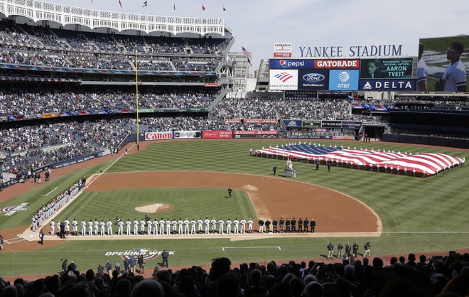 In this March 28, 2019, file photo, a large flag is unfurled during the national anthem before an opening day baseball game between the New York Yankees and the Baltimore Orioles at Yankee Stadium in New York. A pair of fans in New York sued Major League Baseball, Commissioner Rob Manfred and the 30 teams, asking for their money back for tickets and for certification of class-action status.

 [AP File Photo/Seth Wenig]
