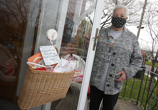 Mary (Brio) Rose stands on the porch of her Massillon home next to a basket filled with masks that she has sewn. The sign tells visitors to take a mask if they need one. (IndeOnline.com / Kevin Whitlock)