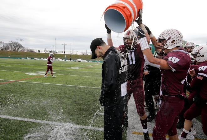 Woonsocket football coach Charles Bibeault gets a congratulatory soaking from players Emmanuel Gomes and Zachary MacIntyre in November 2018 after the Villa Novans won the Division II Super Bowl at Cranston Stadium. With the realignment approved Thursday, Woonsocket moves to Division I. [The Providence Journal, file / Kris Craig]