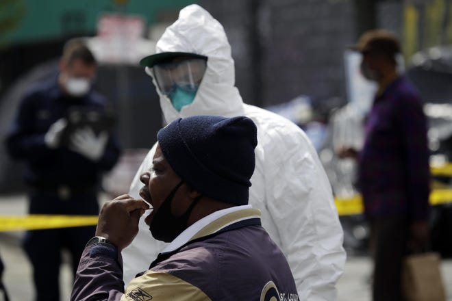 A man swabs his mouths while taking a COVID-19 test in the Skid Row district in Los Angeles. [MARCIO JOSE SANCHEZ/AP]