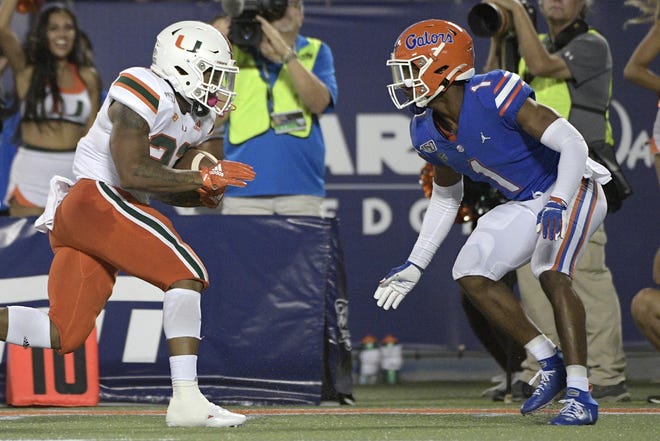 Florida defensive back CJ Henderson (1) defends as Miami running back Cam'Ron Harris rushes for yardage in the Aug. 24 game last year in Orlando. [Phelan M. Ebenhack/The Associated Press/File]