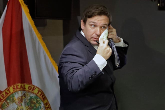 Florida Gov. Ron DeSantis puts on a safety mask after a COVID-19 news conference Monday, April 27, 2020, at the Tampa General Hospital in Tampa, Fla. (AP Photo/Chris O'Meara)