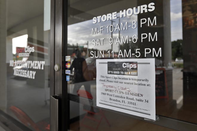 A woman is reflected in the glass of a shuttered hair stylist Thursday, April 23, 2020, in Riverview, Fla. Businesses that were deemed not essential by the state were forced to temporarily close and their employees were either furloughed or layed off. The move was an attempt to avoid spreading the coronavirus. (AP Photo/Chris O'Meara)