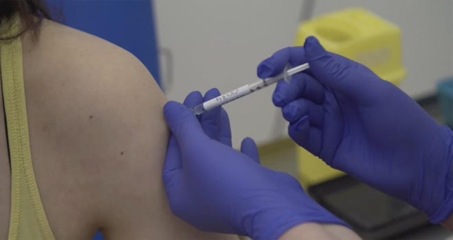 A women is injected as part of the first human trials to test a potential coronavirus vaccine, undertaken by Oxford University in England. [Oxford University Pool via AP]