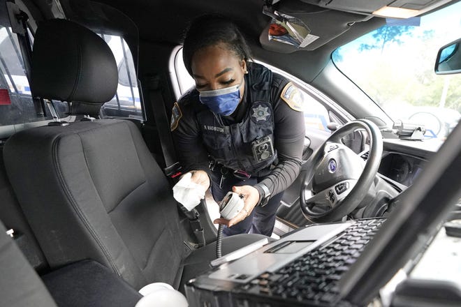 In this April 17 photo, Harris County Sheriff's Deputy Ravin Washington wipes the microphone inside her patrol car before starting her patrol in Spring, Texas. [David J. Phillip/The Associated Press]