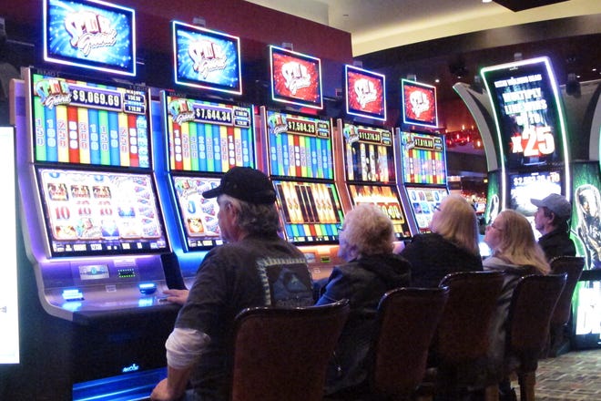 In this Feb. 22, 2019 photo, gamblers play slot machines in the Golden Nugget Casino in Atlantic City, N.J. Every second or third slot machine might be turned off or made inaccessible in some casinos as they adapt to the coronavirus outbreak in preparing to reopen. Many casinos plan more frequent sanitization of slot machines once they reopen. (AP Photo/Wayne Parry)
