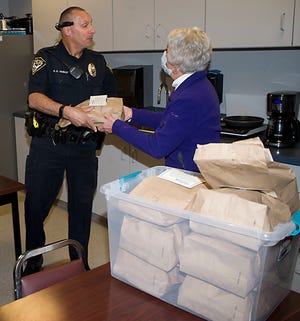 Alliance Police officer Ken Hanket assists Alliance Kiwanis Club board member Lynda Slack with the distribution of breakfast meals Thursday in the dining area at the Alliance Police Department.