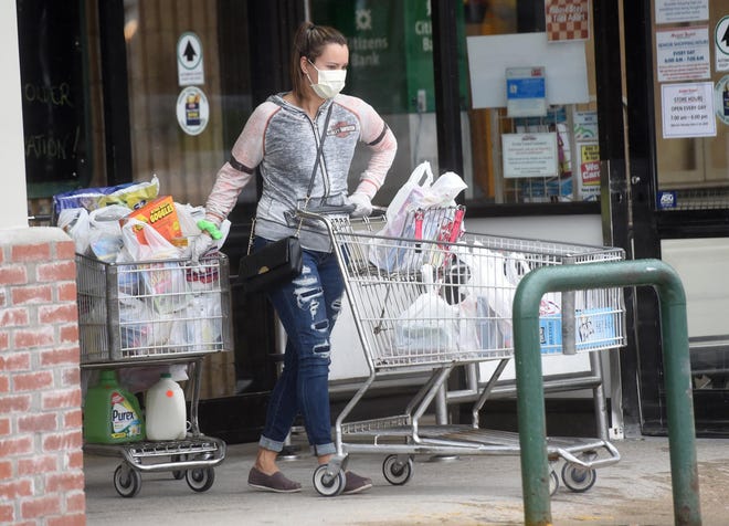 Katelyn Butterfield of South Berwick, Maine, seen in a file photo from earlier this month, leaves the Market Basket store on Woodbury Avenue in Portsmouth with two carts wearing a protective mask. She is shopping for her mother, 55, and grandmother, 71, who also has chronic obstructive pulmonary disease. Butterfield says, "Due to my grandmother's illness, we've got to keep her out of the stores." [Deb Cram/Seacoastonline and Fosters.com]