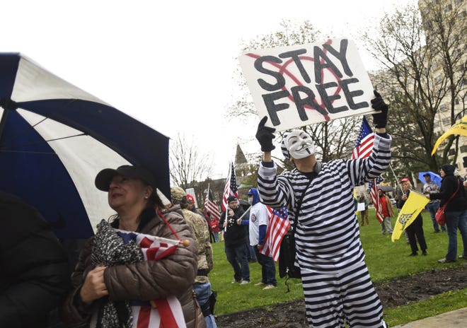 Protesters rally at the state Capitol in Lansing, Mich., Thursday, April 30, 2020. Hoisting American flags and handmade signs, protesters returned to the state Capitol to denounce Gov. Gretchen Whitmer's stay-home order and business restrictions due to COVID-19, while lawmakers met to consider extending her emergency declaration hours before it expires. (Matthew Dae Smith/Lansing State Journal via AP)