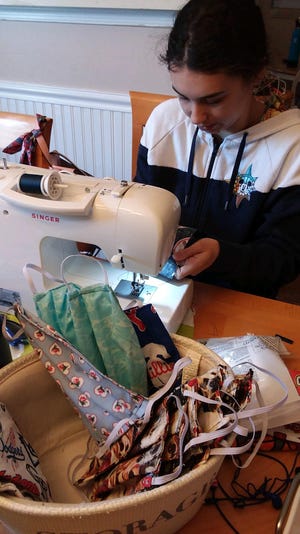 Eastampton resident Kaitlyn Orzol sews protective masks at her family’s kitchen table. [CONTRIBUTED]