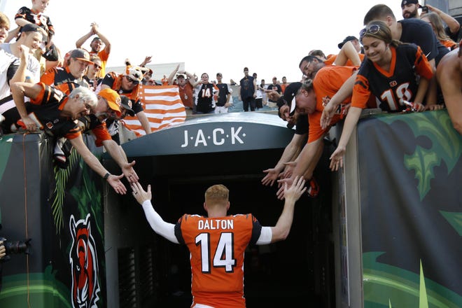 Bengals quarterback Andy Dalton gives high-fives to fans at Paul Brown Stadium after a 2018 game. Dalton leaves Cincinnati with a 70-61-2 record as a starter. [Associated Press file photo]