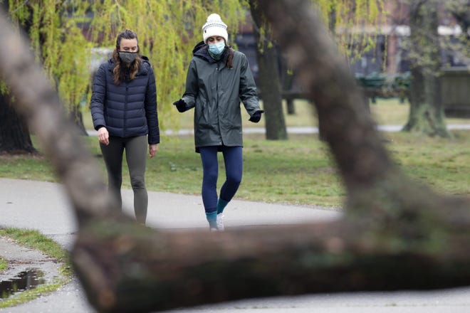 Two women wearing protective masks walk on the Esplanade on Friday in Boston.  [AP Photo]