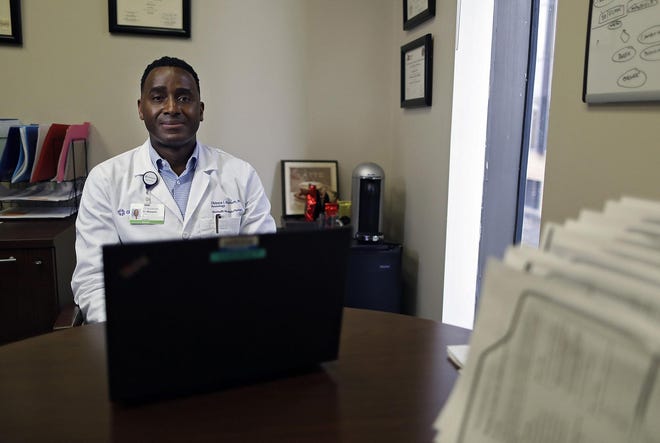 Dr. Obi Moneme, a neurologist, poses for a photo with his laptop that he uses for video conferences with patients at OhioHealth Neurological Physicians in Columbus on April 28, 2020. [Kyle Robertson/Dispatch]