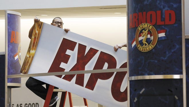 Workers dismantle the signage outside the entrance to the Arnold Sports Expo on March 4, after the state closed the event to spectators because of the coronavirus outbreak. [Joshua A. Bickel/Dispatch]