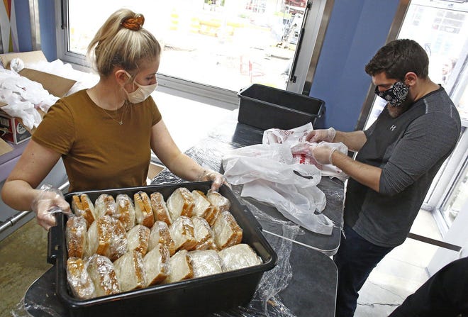 Taylor Leach, left, and Tyler Andrews pack free Make-A-Day meals at Goody Boy Diner in the Short North on Thursday. [Fred Squillante/Dispatch]