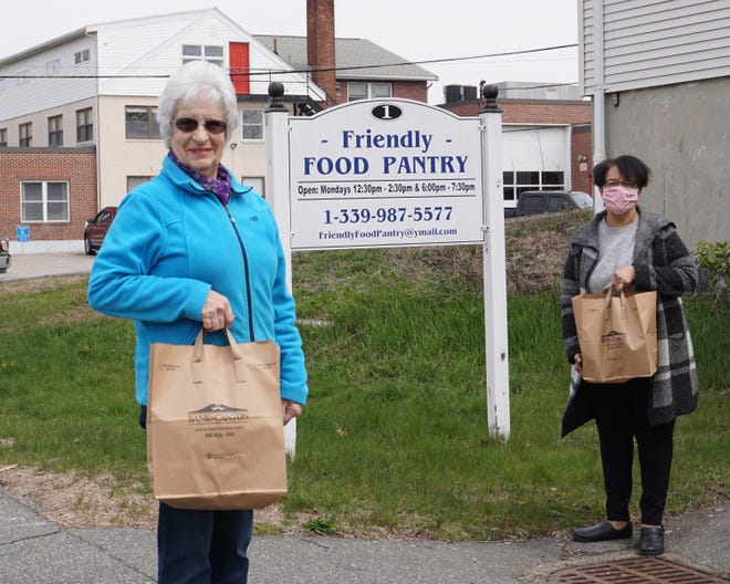 Friendly Food Pantry Assistant Director Janet Lynch (left) and volunteer Julia Mosely carry bags donated by the Bank of Canton. [Courtesy photo]