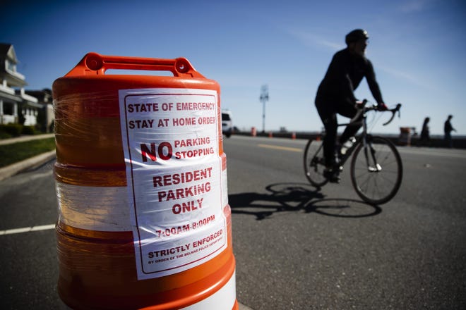 A cyclist rides past a traffic barrel posted with a sign restricting parking to residents only in Belmar on Saturday. [AP Photo/Matt Rourke]