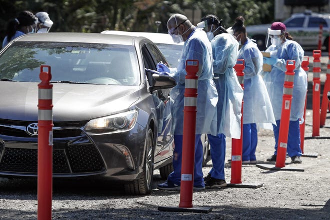 Health workers conduct COVID-19 tests at a drive through coronavirus testing site at a community center April 27 in Sanford. [AP Photo/John Raoux]