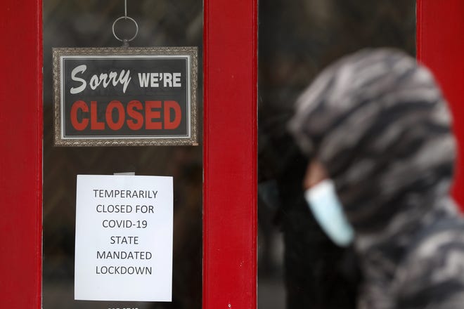 A pedestrian walks by The Framing Gallery, closed due to the COVID-19 pandemic, in Grosse Pointe, Mich.  [AP Photo]