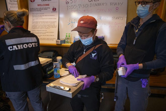 Vé Gulbrandsen, center, an EMT with CAHOOTS, joins a team from White Bird in screening guests for health concerns at the Egan Warming Center's Springfield location in mid-March. [Chris Pietsch/The Register-Guard file] - registerguard.com