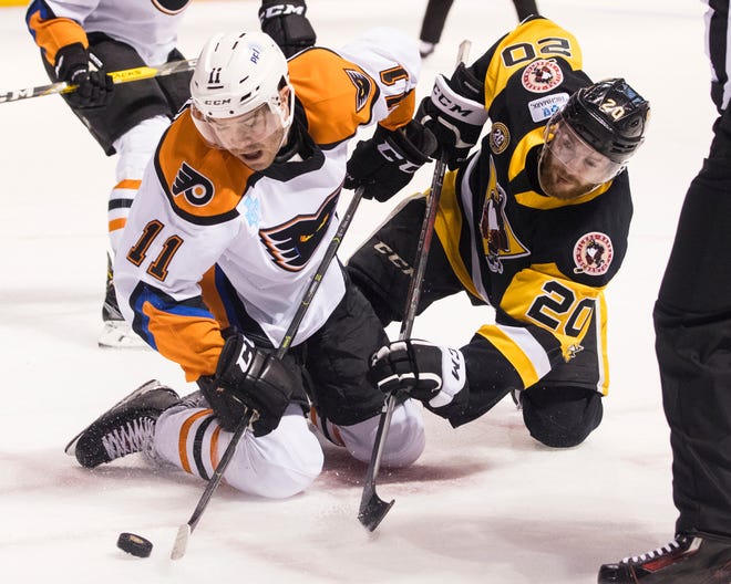 In this March 16, 2019, file photo, Lehigh Valley Phantoms' Steven Swavely (11) moves the puck past the Wilkes-Barre/Scranton Penguins' Jarrett Burton after a faceoff during an AHL hockey game at Mohegan Sun Arena in Wilkes-Barre, Pa. The American Hockey League has canceled the rest of its season because of the coronavirus pandemic. President and CEO David Andrews announced the league ‘has determined that the resumption and completion of the 2019-20 season is not feasible in light of current conditions.’ The AHL's Board of Governors made that determination in a conference call Friday, May 8, 2020. [Christopher Dolan/The Citizens' Voice via AP, File]