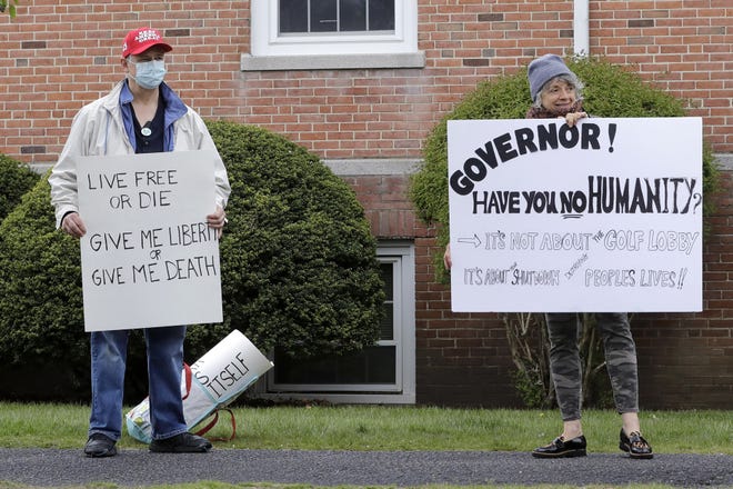 Protesters display placards while demonstrating against the shutdown caused by the COVID-19 virus outbreak, near the home of Massachusetts Gov. Charlie Baker, in Swampscott, Mass., Monday, May 11, 2020. (AP Photo/Steven Senne)