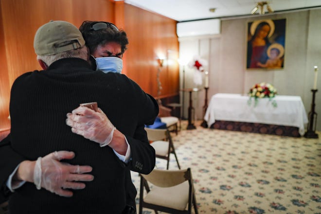 Leonardo CabaÃ±a cries in the arms of his friend Raphael Benevides beside the casket of his father, HÃ©ctor Miguel CabaÃ±a, who died of COVID-19 before the funeral home service led by the Rev. Fabian Arias, Monday, May 11, 2020, in the Brooklyn borough of New York. In hard-hit New York City, the coronavirus outbreak has taken a particularly heavy toll on Hispanic communities. (AP Photo/John Minchillo)