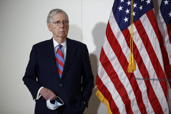 Senate Majority Leader Mitch McConnell of Ky., holds a face mask used to protect against the spread of the new coronavirus as he attends a news conference on Capitol Hill in Washington, Tuesday, May 12, 2020. [Patrick Semansky/ASSOCIATED PRESS]