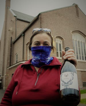 Denise Fitzmaurice holds a bottle of wine during a recent mystery wine grab. The wine was a gift from her husband, Curt Fitzmaurice, to Immaculate Heart of Mary Church in Winchendon. Church members promoted a mystery wine grab online and people came to purchase a bottle or two to support the parish and all it does in the community. Denise was one of those responding as people came to pick up the mystery wine. [News staff photo by Doneen Durling]