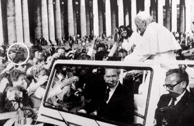 A hand holding a gun at left, aims from the crowd at Pope John Paul II as he rides through St. Peter's Square at the Vatican on May 13, 1981. An instant later, the pontiff was shot. [ADN Kronos/The Associated Press]