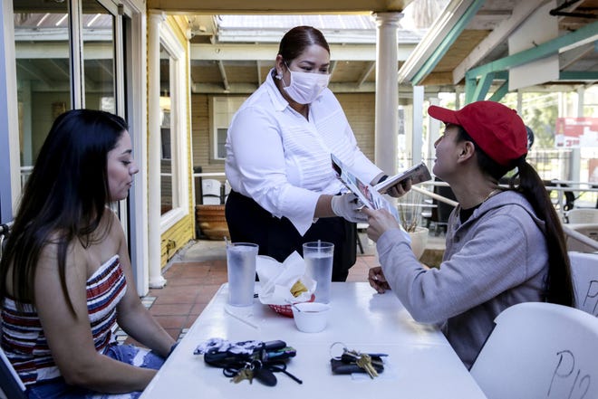 Dayana Solia takes menus from customers Lexie Belcher and Aleza Ruiz at Austin’s Juan In a Million restaurant earlier this month. Area restaurants are hoping they will see a boost when local technology workers start returning to their offices.  [BRONTE WITTPENN/AMERICAN-STATESMAN/FILE]