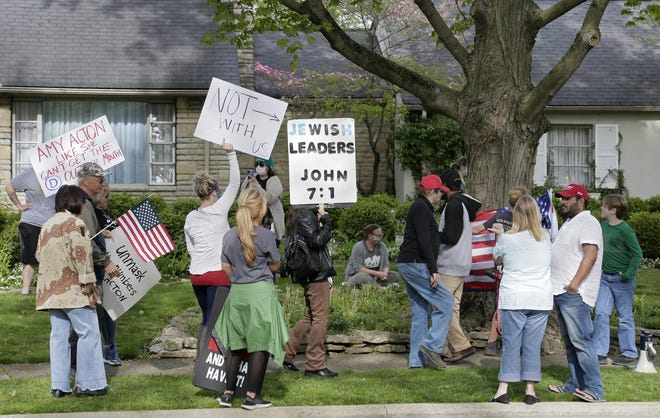 Supporters of Ohio Health Director Dr. Amy Acton form a "friend chain" on Acton's front lawn after a few dozen protesters of the stay-at-home orders once again showed up outside her home in Bexley, Ohio, Monday, May 4, 2020. The State Highway Patrol now has officers posted at Acton's house. (Barbara J. Perenic/The Columbus Dispatch via AP)