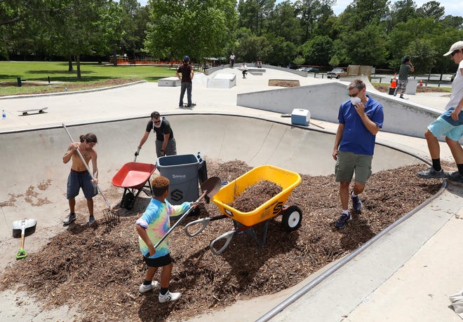 Adults and kids shovel mulch into wheelbarrows as they try to remove hundreds of yards of mulch filling the pool at the Possum Creek Skate Park Friday. City workers had placed mulch to cover the skatepark to deter kids from using the skateboard facility after the park recently reopened. Local young skaters and some adults worked all day to clear the mulch off the skatepark. But by the evening city personnel put up signs saying the park was closed. Gainesville police got the kids to leave with no issues. [Brad McClenny/Staff photographer]
