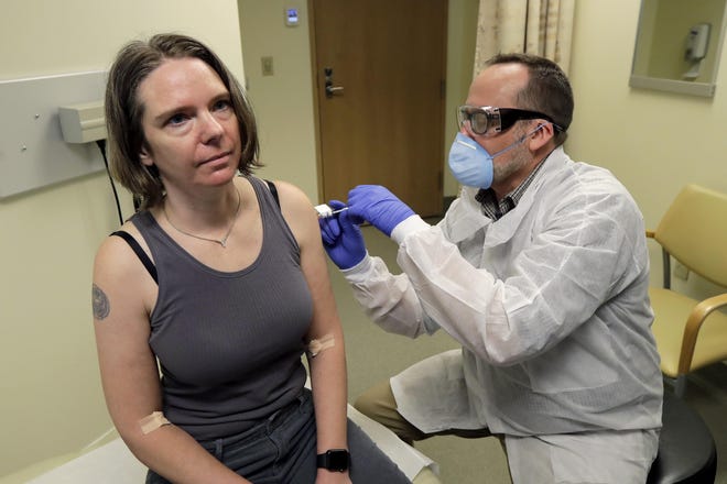 Jennifer Haller, left, is given the first shot in the first-stage safety study clinical trial of a potential vaccine for the COVID-19 coronavirus by a pharmacist, Monday, March 16, 2020, at the Kaiser Permanente Washington Health Research Institute in Seattle. [AP Photo/Ted S. Warren]