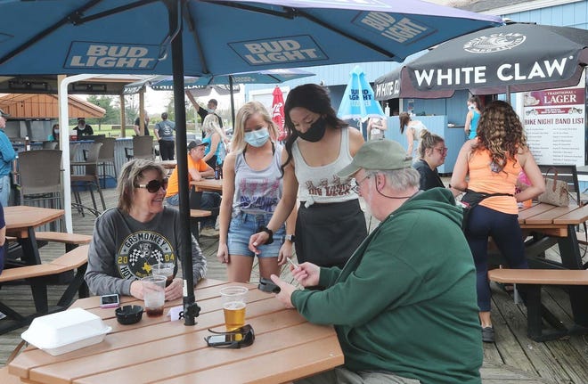 Lynn Smead, left, and her friend Brad Smith talk with servers Brianah Mastriano, center left, and Gabrielle O'Neal at the Upper Deck Bar & Grill in New Franklin on Friday. [Karen Schiely/Beacon Journal]