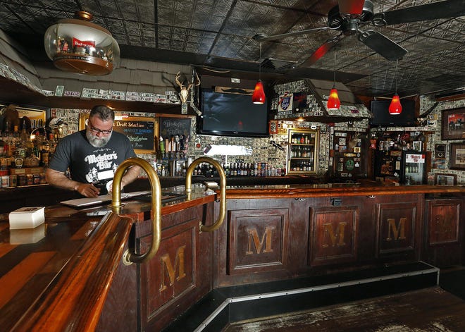 Todd Meister, owner of Meister's Bar near Grandview Heights, does some bookkeeping at the now-seatless bar. Customers respected social distancing guidelines when the bar opened its patio Friday, said Meister, and he expects that trend to continue Thursday when the inside reopens.[Eric Albrecht/Dispatch]