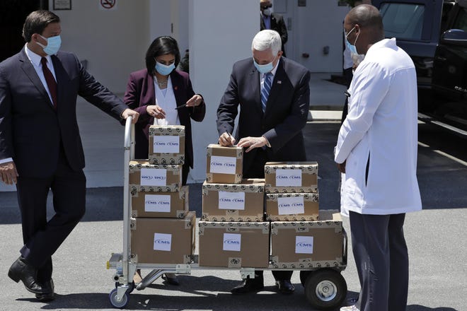 Vice President Mike Pence, second from right, writes on a box after delivering personal protective equipment to the Westminster Baldwin Park, Wednesday in Orlando, as part of the initiative to deliver PPE to more than 15,000 nursing homes across America. Looking on is Florida Gov. Ron DeSantis, left, Seema Verma, the Administrator for the Centers for Medicare and Medicaid Services, second from left, and Healthcare Administrator Fanley Romelus, right. [AP Photo/Chris O'Meara]