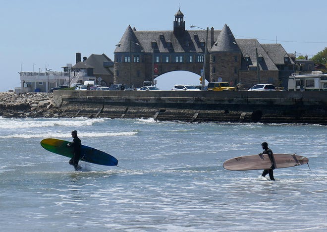 Two surfers head out from Narragansett Town Beach in search of waves on Thursday. The beach is not yet open, but already its popularity is evident. [The Providence Journal / Sandor Bodo]