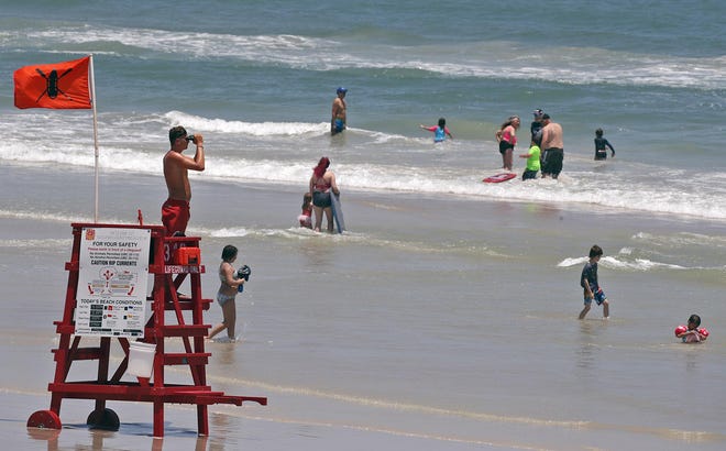 A Volusia County Beach Lifeguard watches the waters from his tower on the beach in Daytona Beach on Friday. The National Weather Service says the risk of rip currents and rough surf will be throughout the Memorial Day weekend. [News-Journal/Nigel Cook]