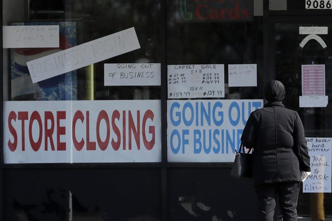 A woman looks at signs at a store closed due to COVID-19 in Niles, Ill., Wednesday, May 13. [AP Photo/Nam Y. Huh]