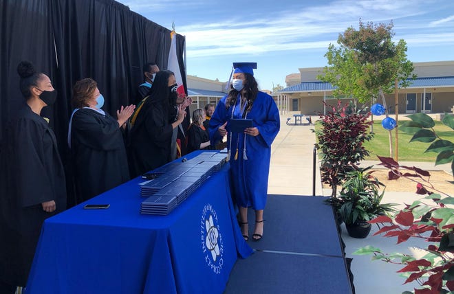 A Cobalt Institute of Math & Science graduate picks up her diploma after posing for photos during the school’s drive-thru graduation ceremony at the CIMS campus on Friday, May 22, 2020. [PHOTO COURTESY OF VVUHSD]