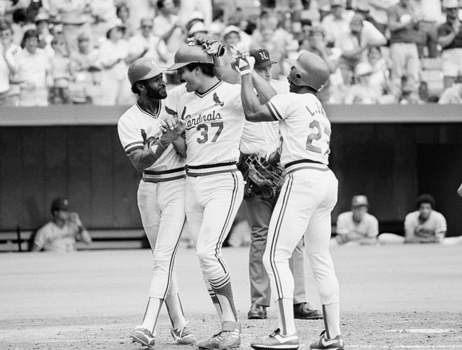 St. Louis Cardinals first baseman Keith Hernandez is congratulated at the plate by teammates Ozzie Smith, left, and Lonnie Smith after hitting a three-run home run in the second inning of their game with the Cincinnati Reds in St. Louis on July 19, 1982. The Cards won 6-5. [AP Photo/James Finley]
