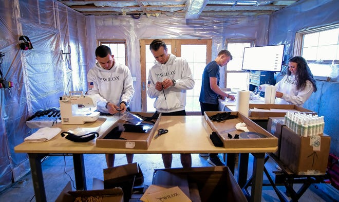 From left, Paul Wiley, his cousin Luke Knox and his siblings, Matt Wiley and Mary Anne Wiley form an assembly line in the basement of the Wiley home in Bow, New Hampshire, earlier this month, making their custom Wilox masks for medical use. The name was formed with the combination of the cousins' last names. [Photo/Geoff Forester, Concord Monitor]