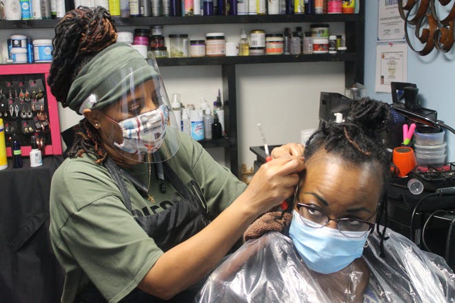 Antoinette Black, left, owner of A Nu Twist Salon located at 1031 NW Sixth St., Suite B3, twists Valerie Greene's locs during her hair appointment. Greene has been Black's client for 30 years. [Photos by Voleer Thomas/For The Guardian]
