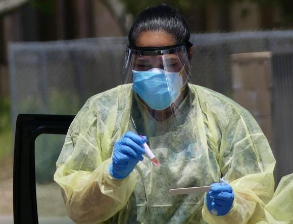 A San Bernardino County worker carries a COVID-19 test sample taken in Apple Valley on April 30, 2020 [RENE RAY DE LA CRUZ/DAILY PRESS]