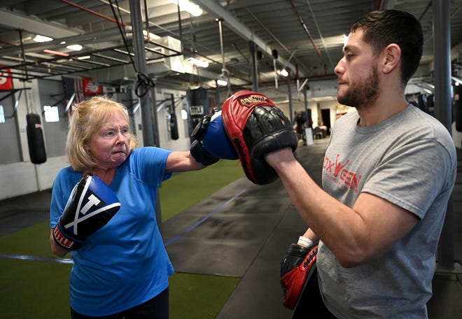 Before the COVID-19 pandemic hit, Kathleen Corcoran of West Roxbury threw a punch at Cambridge resident Rafael Rivera, her boxing coach, during a Rock Steady boxing class for people with Parkinson's disease at the Nonantum Boxing Club in Newton. Corcoran was diagnosed in 2006. [Daily News and Wicked Local Staff Photo/Ken McGagh]