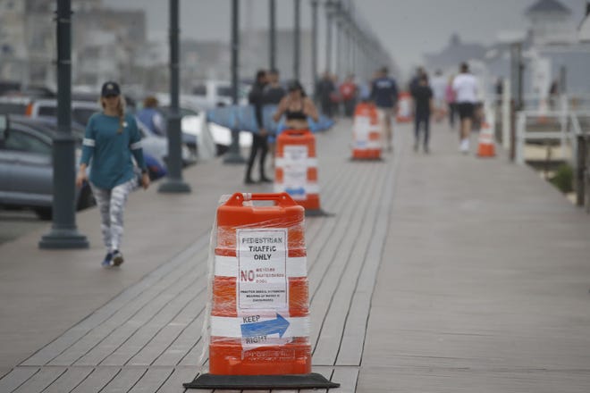 People walk along a boardwalk at a mostly empty beach Saturday, May 23, 2020, in Belmar during the coronavirus pandemic. (AP Photo/John Minchillo)