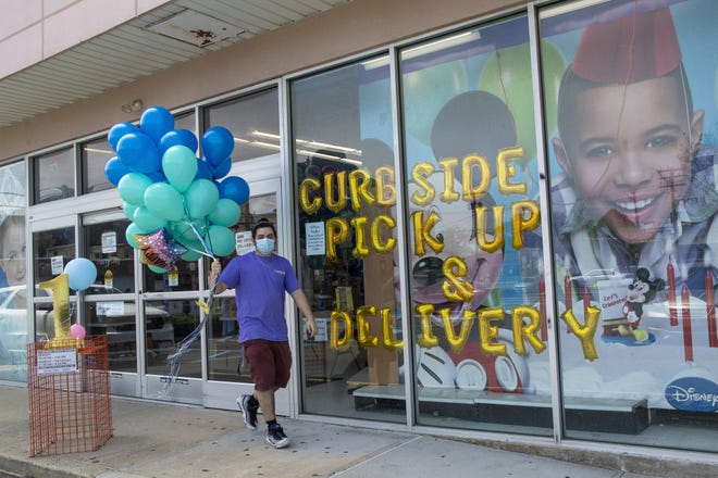 A Party City employee delivers balloons to a customer curbside, Wednesday, May 27, 2020, in Oceanside, N.Y. Long Island has become the latest region of New York to begin easing restrictions put in place to curb the spread of the coronavirus as it enters the first phase of the state's four-step reopening process. [AP Photo/Mary Altaffer]
