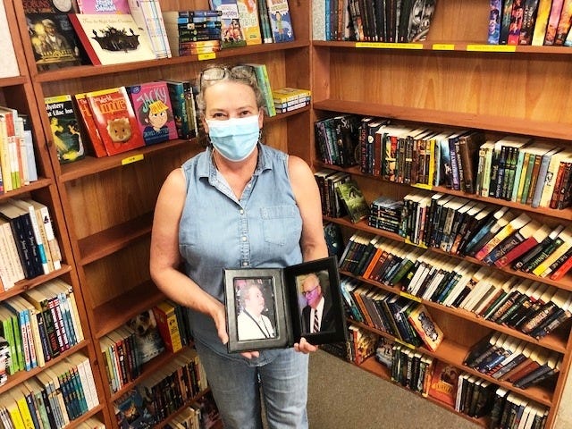 Ann Durant, owner of Annie's Book Stop in Plainville, has made the difficult decision to close her store in the face of the coronavirus pandemic. The nearly 40-year-old business was originally owned by her mother, the late Eleanor Arnold, whose photo she holds in a frame opposite a photo of her dad, Ralph. She is surrounded by emptying shelves in the store at Man-Mar Drive. [WICKED LOCAL STAFF PHOTO/Heather McCarron]