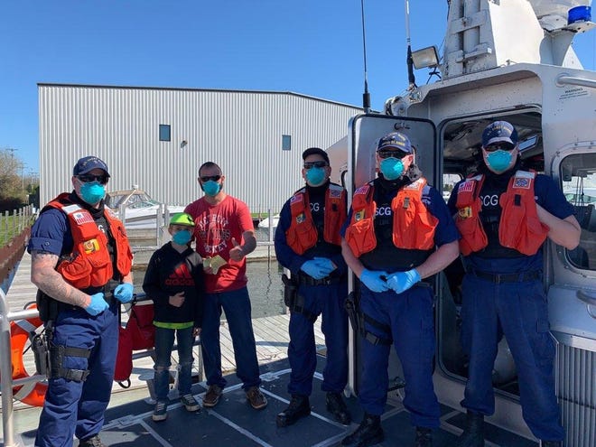 After helping rescue the man and his son from the Cheboygan River, crew members of the United States Coast Guard Station St. Ignace took time to take photos with the family. Contributed photo